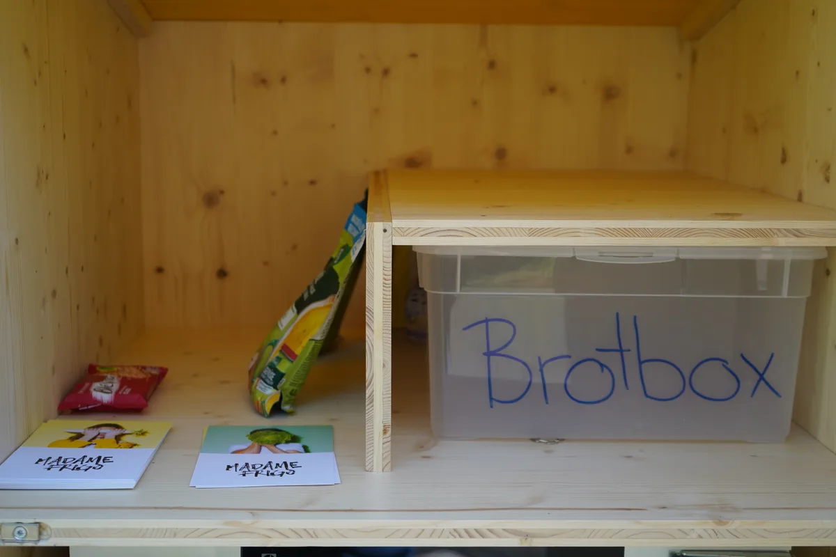 Ein Holzschrank mit Utensilien wie beispielsweise einer Plastikbox.